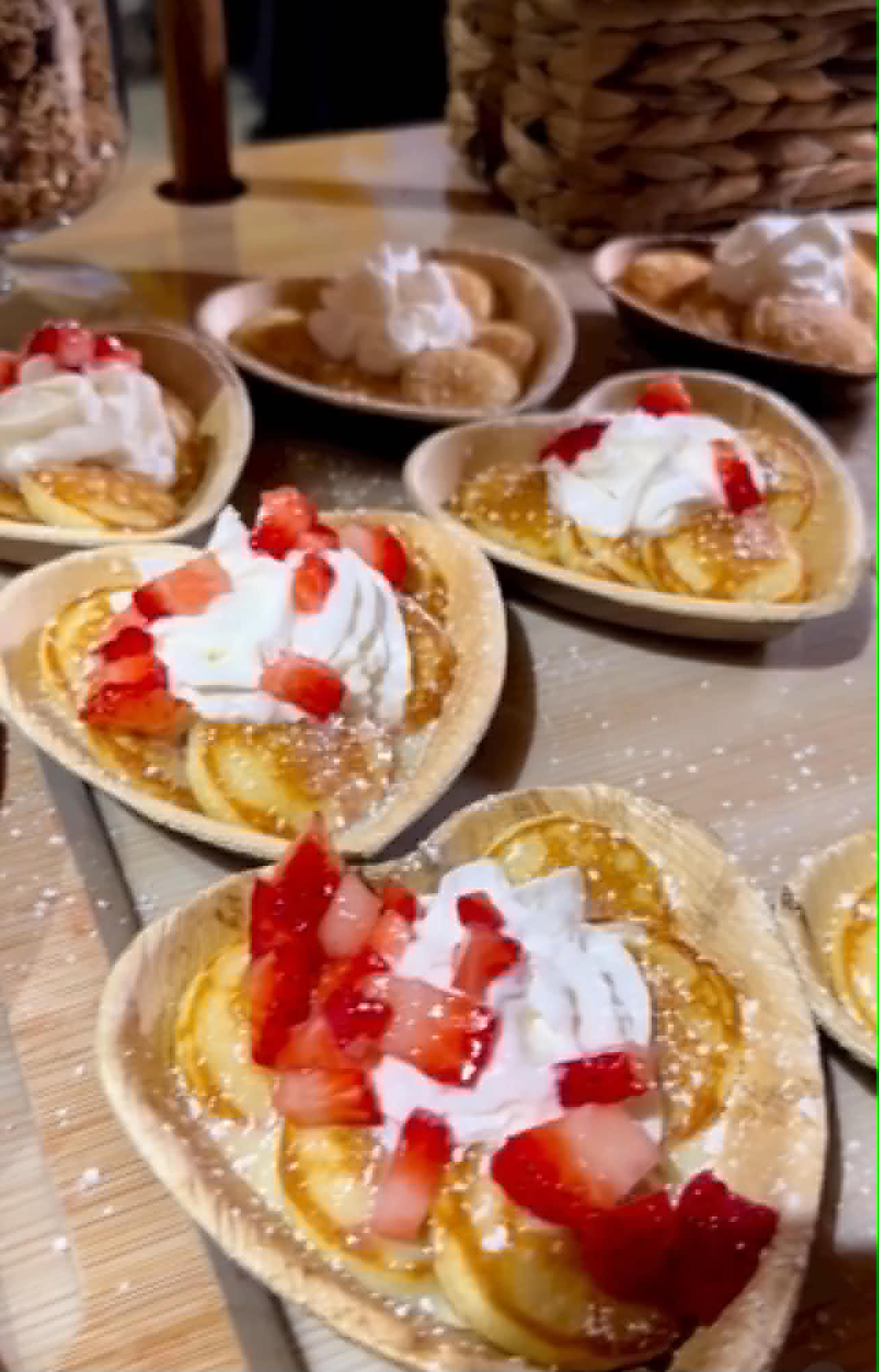 Mini pancakes topped with strawberries and whipped cream served in heart-shaped bowls