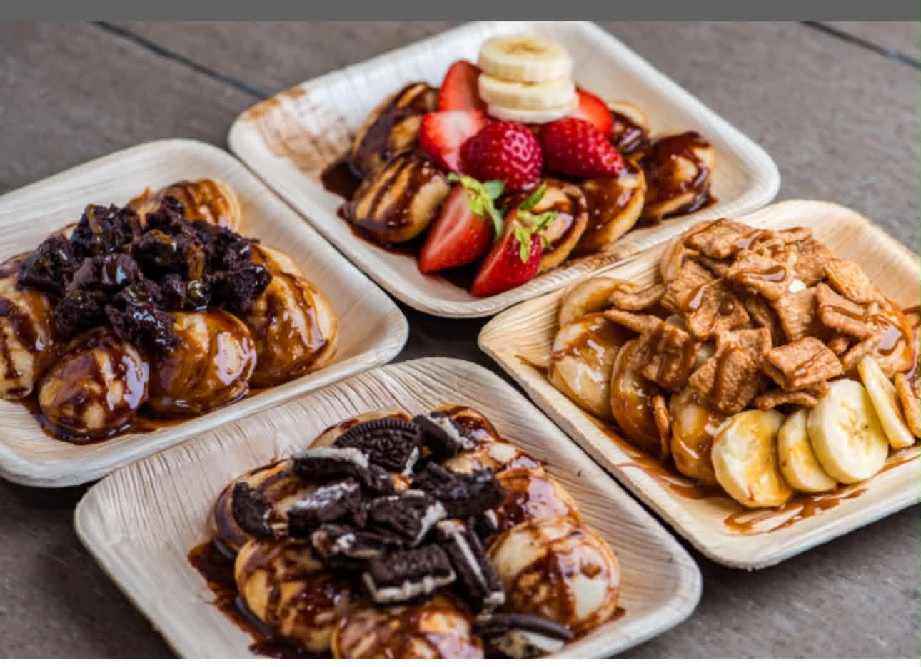 Mini pancake trays with custom toppings — brownie bites, strawberry banana, cinnamon cereal, and Oreo